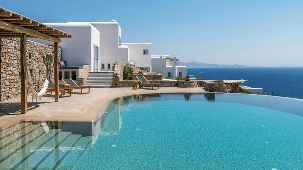Ein Resort mit Infinity-Pool, weißen Gebäuden und Meerblick.