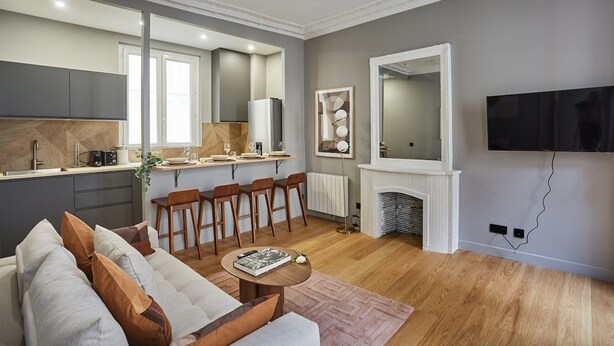 Una sala moderna con un sofá, una mesa de centro y una chimenea. Hay una zona de cocina con una mesa de comedor y sillas.