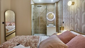 Un dormitorio moderno con una cama grande, un tocador con espejo y una zona de ducha.