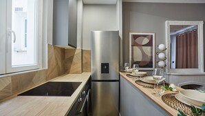 Una cocina moderna con un refrigerador de acero inoxidable, horno empotrado y cocina negra.