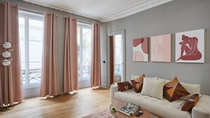 Una sala de estar con sofá, mesa de centro y una obra de arte en la pared.