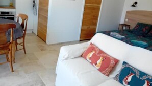 Una habitación con una cama, una puerta de madera, un cuadro enmarcado en la pared y una pequeña mesa con una silla.
