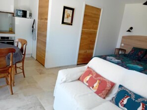 A room with a bed, a wooden door, a framed picture on the wall, and a small table with a chair. - Modern studio with WiFi and parking in Baignes (Baignes-Sainte-Radegonde)