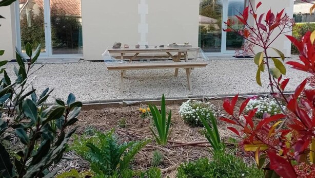 Un edificio moderno con un patio, una mesa y un banco.