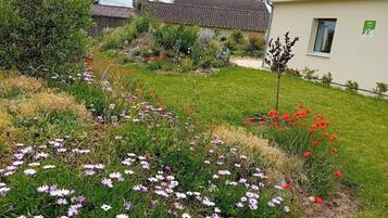 A garden with various flowers and a building with a tiled roof.