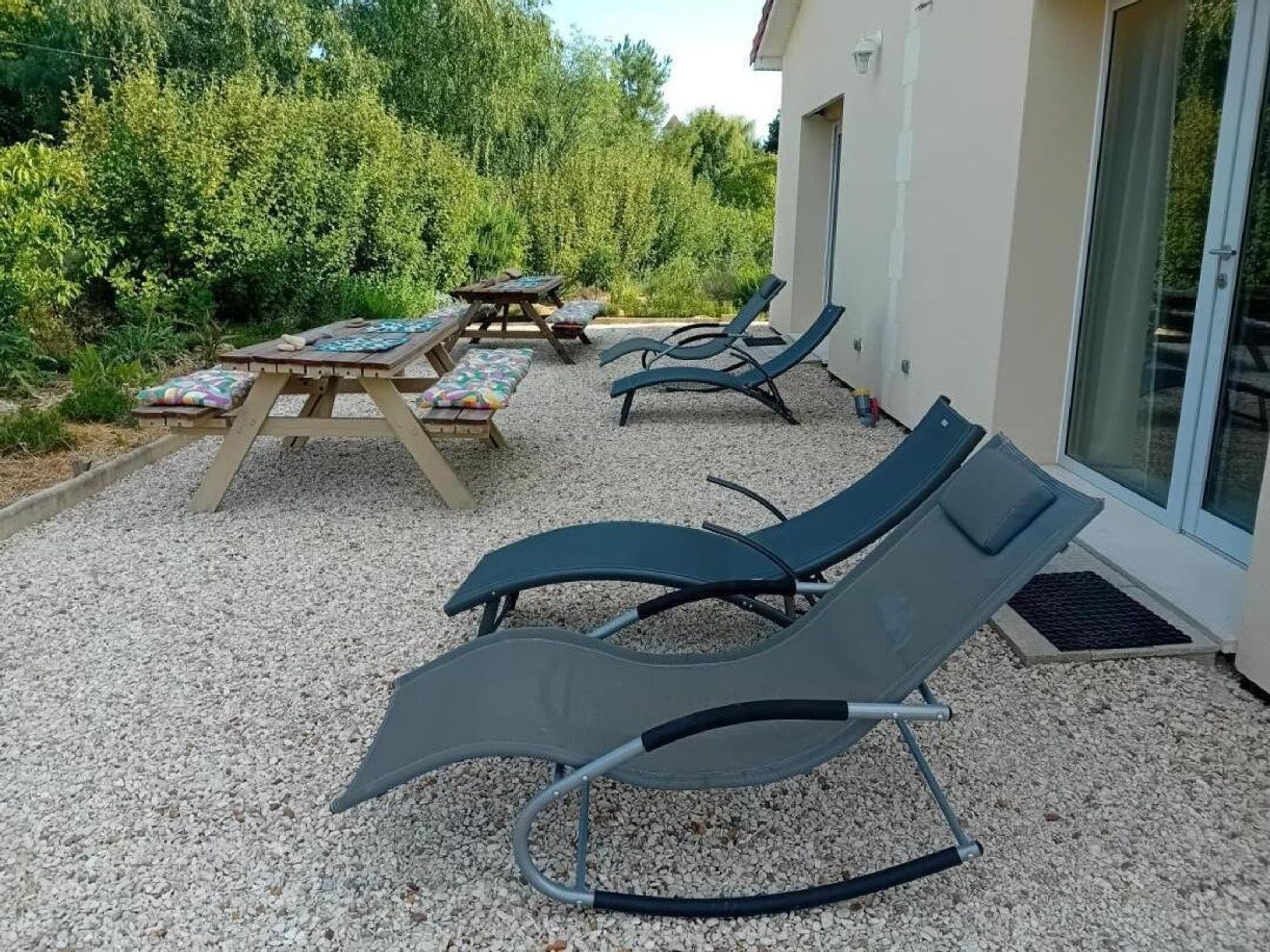 A patio area with outdoor seating, including lounge chairs and a table with a bench.
