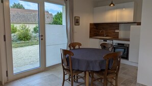 Una cocina compacta con zona de comedor, una puerta corrediza de vidrio que da a un patio y una lámpara colgante.