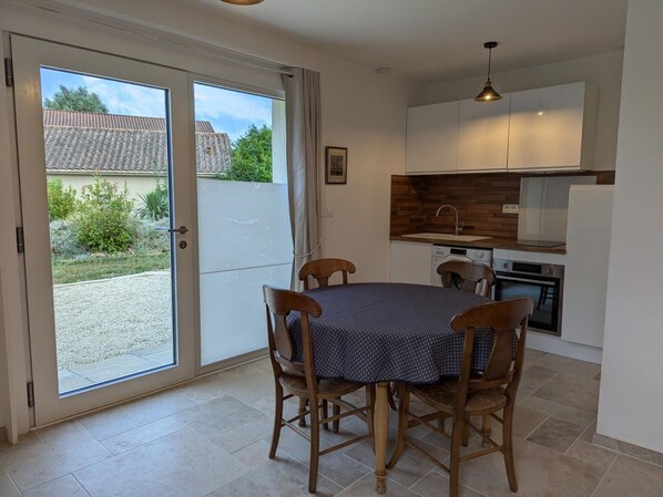 A compact kitchen with a dining area, a sliding glass door leading to a patio, and a hanging pendant light. - Modern studio with WiFi and parking in Baignes (Baignes-Sainte-Radegonde)