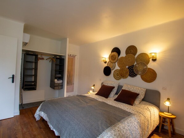 Une chambre à coucher comprenant un lit, des lampes de chevet, un luminaire fixé au mur et une armoire.