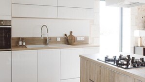 A modern kitchen with white cabinetry, a stainless steel sink, a gas stove, and a window providing natural light. - Charming house with air conditioning, WiFi and pets allowed in Puycousin (Sorges et Ligueux en Périgord)