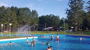 Una piscina pública con gente nadando y descansando.
