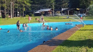 Un área de piscina con varias piscinas, rodeada de zonas verdes y árboles.