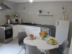 Uma cozinha moderna com mesa de jantar, cadeiras, micro-ondas, fogão e geladeira.