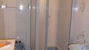 Une salle de bain avec un lavabo bleu, des toilettes et un espace douche.