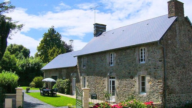 A stone building with a sloped roof, a small garden with red flowers, and a table and chairs outside. - Family house in Gouville-sur-Mer, near the English Channel, pets allowed (Gouville-sur-Mer)