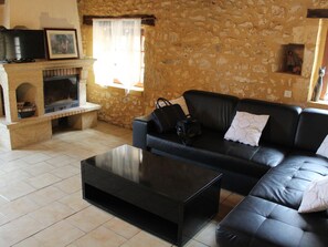 A living room with a stone wall, a fireplace, a black leather sofa, and a coffee table.