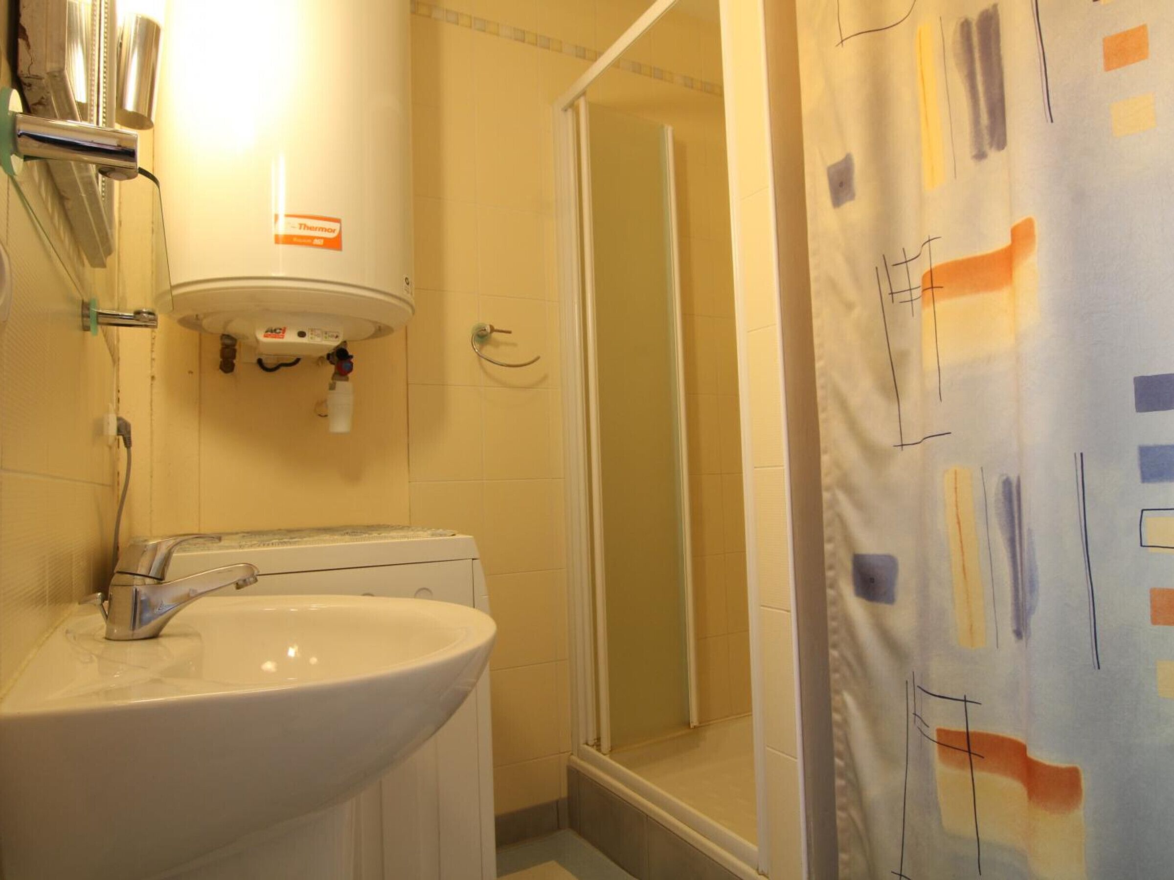 A bathroom with a white sink, a mirror, and a shower.