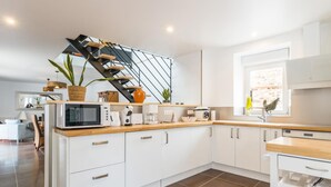 A modern kitchen with white cabinets, a wooden countertop, and a black staircase. - Charming rental in La Hague with private garden, pets allowed (La Hague)