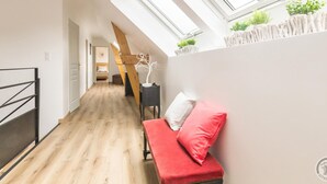 A narrow hallway with wooden flooring, a red bench with white cushions, and a skylight above. - Charming rental in La Hague with private garden, pets allowed (La Hague)