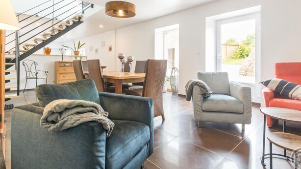 A modern living room with a sofa, armchair, and a dining area with a table and chairs. - Charming rental in La Hague with private garden, pets allowed (La Hague)