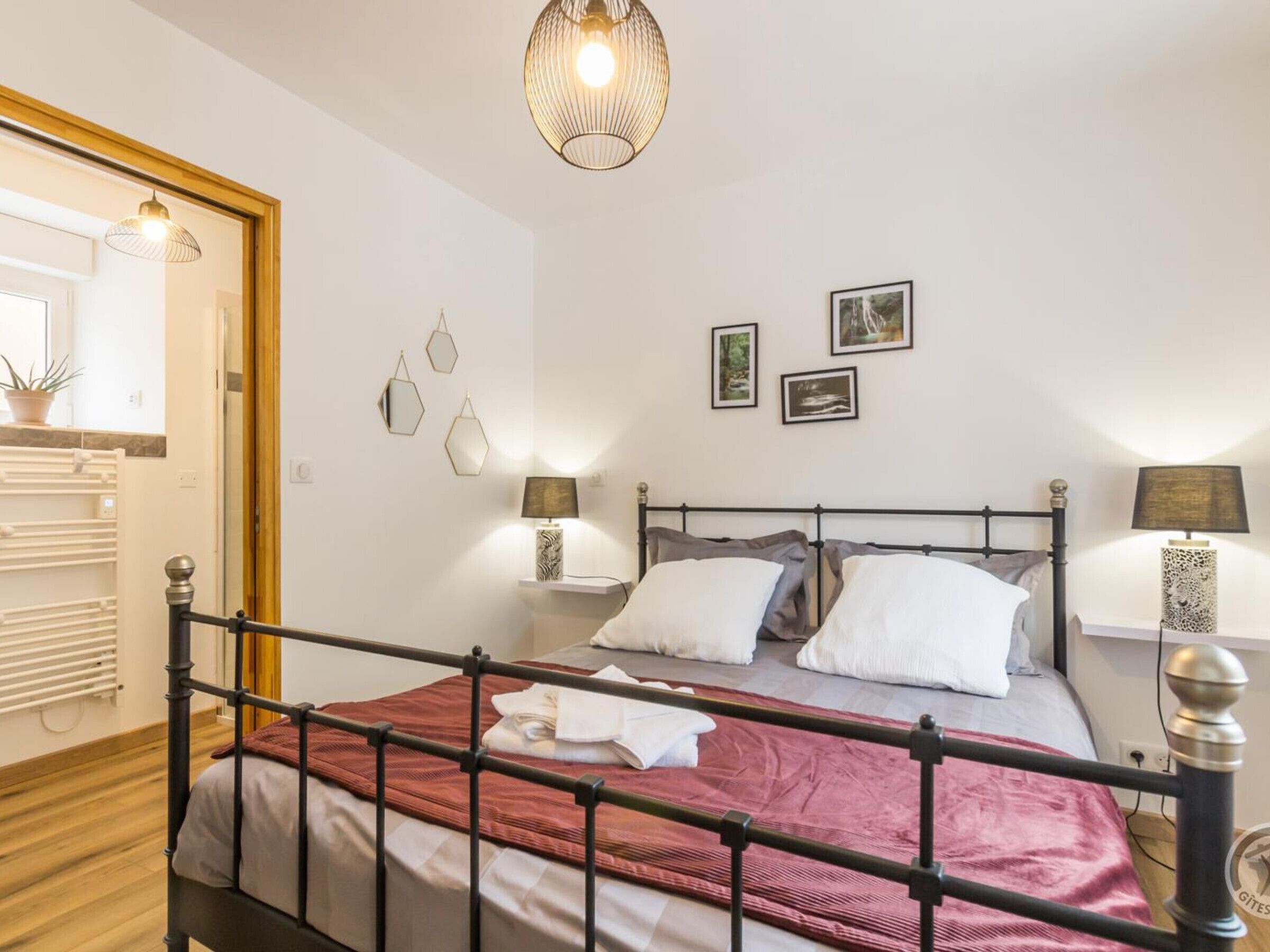 A bedroom with a bed, bedside lamps, a mirror, and wall decorations.