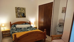 A bedroom with a wooden bed, two bedside tables with lamps, a wooden wardrobe, and a chair.
