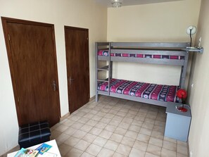 A room with a bunk bed, a desk, a chair, and two doors.