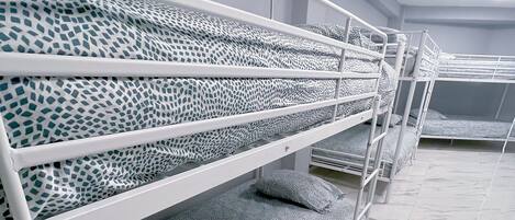 Bunk beds with patterned bedding in a room with white walls and marble flooring.
