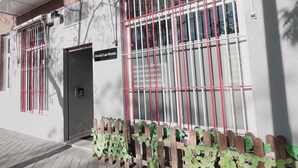 A hostel with barred windows, a sign reading "Hostel Las Rosas," and a wooden fence with plants. - Hostel Las Rosas (Madrid)