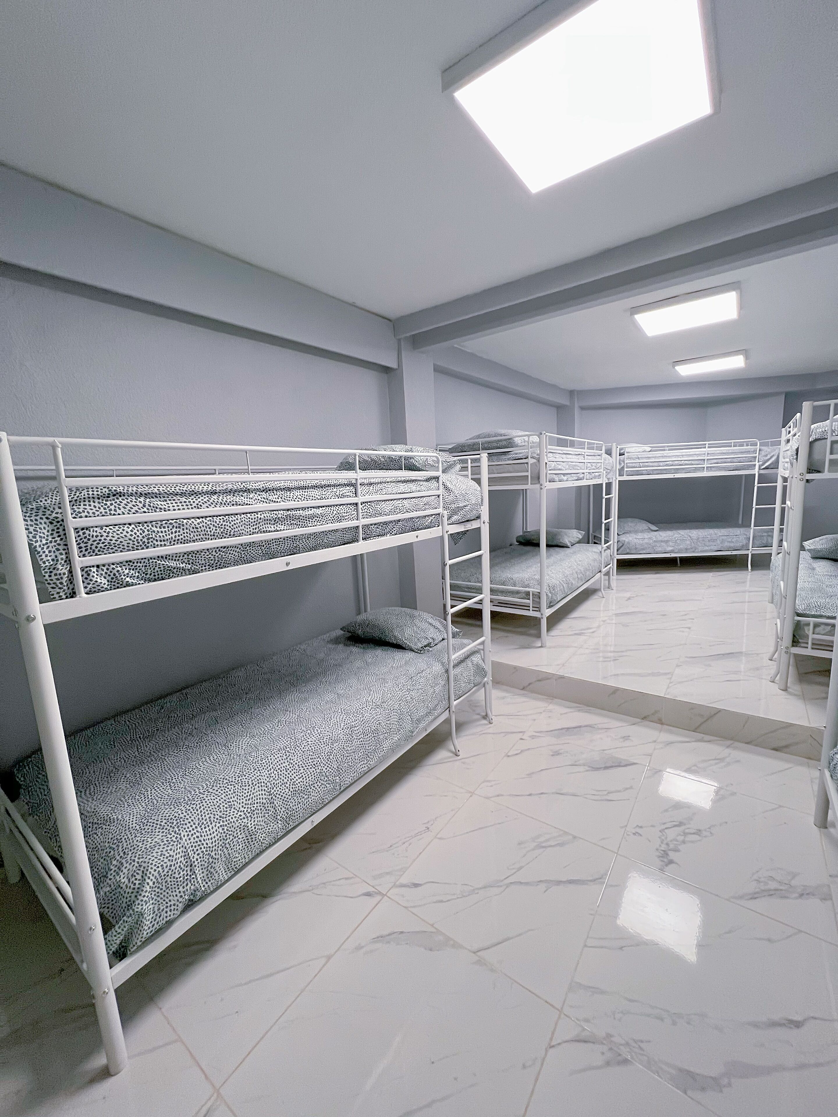Un dormitorio con literas, paredes blancas y suelo de baldosas.