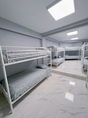 A dormitory room with bunk beds, white walls, and a tiled floor. - Hostel Las Rosas (Madrid)