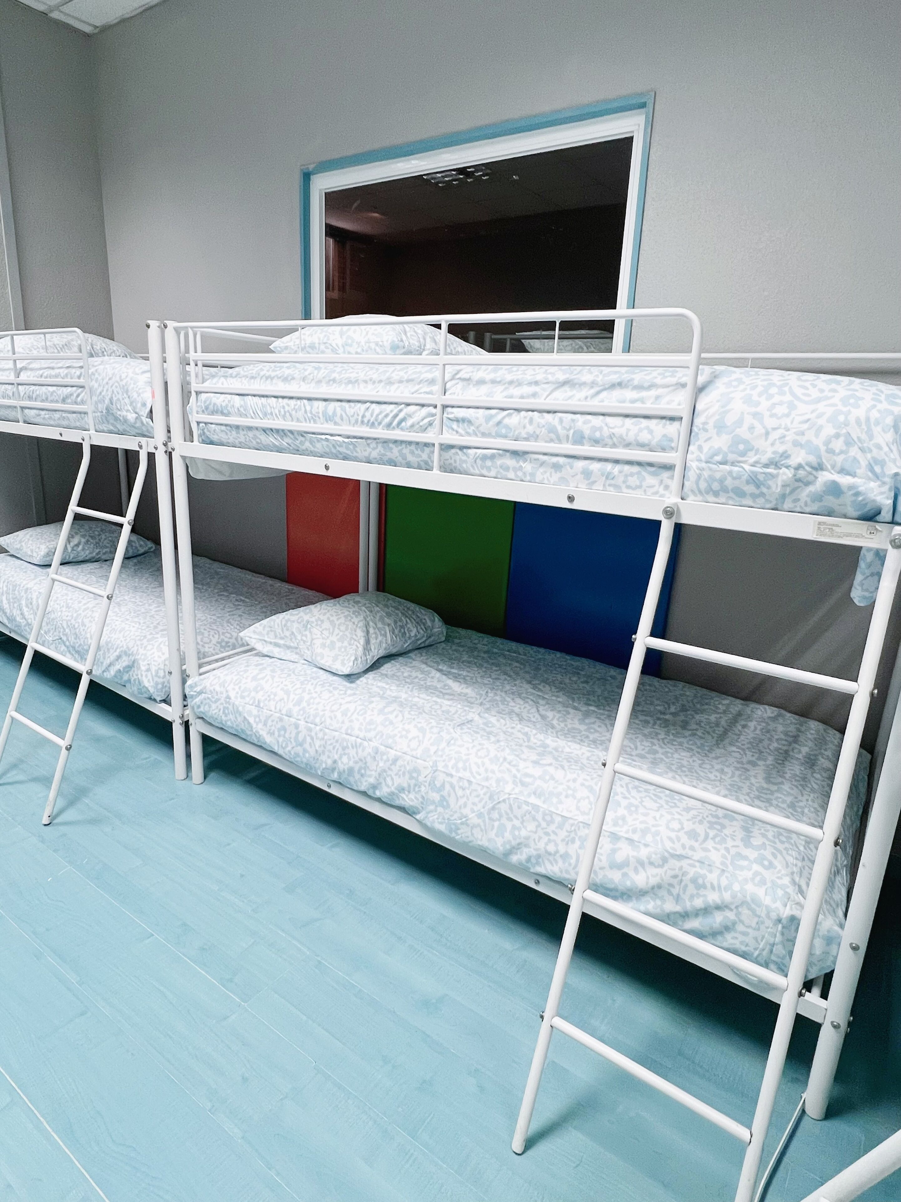 A bunk bed room with a window and a door.
