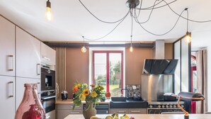 A modern kitchen with a central island, stainless steel appliances, and a view of the outdoors. - Semi-detached house with balcony in countryside, Wi-Fi, parking, pets allowed (Saint-Laurent-de-Terregatte)