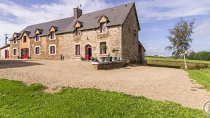 A stone farmhouse with multiple red doors and windows, surrounded by a gravel driveway and grassy areas. - Semi-detached house with balcony in countryside, Wi-Fi, parking, pets allowed (Saint-Laurent-de-Terregatte)