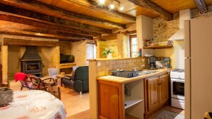 Una cocina rústica con vigas de madera a la vista, una pared de piedra y una estufa empotrada.
