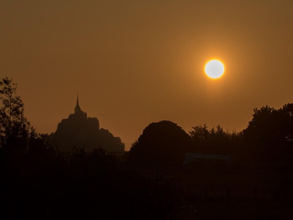 Un atardecer con el silueta de un edificio destacado al fondo.