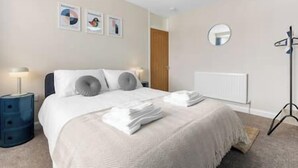 A neatly arranged bedroom with a bed, bedside lamps, a mirror, and a radiator. - NEC Birmingham Airport Modern Village Retreat, Sleeps 7, Free Parking (Hampton in Arden)