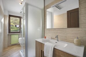 Ein modernes Badezimmer mit einer Glasdusche, einem weißen Waschbecken und einem großen Spiegel.