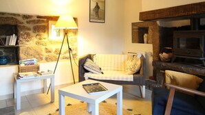 Una sala de estar acogedora con pared de piedra, chimenea, sofá, mesa de centro y lámpara.