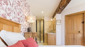A bedroom with a bed, a nightstand, a lamp, a wooden door, and a bathroom visible through an open door. - Charming countryside house with large green area (Marcilly)