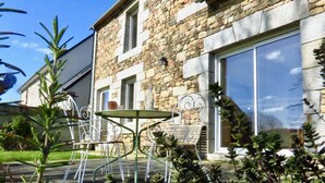 A stone building with a patio area featuring metal chairs and a table. - Charming countryside house with large green area (Marcilly)