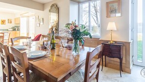 A dining room with a wooden table set for four, a vase of flowers, and a chandelier. - Charming countryside house with large green area (Marcilly)