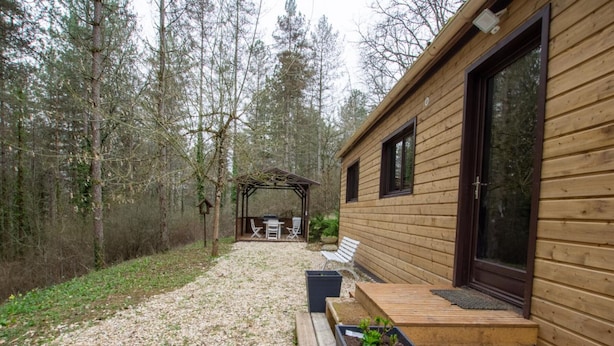 A wooden cabin with a patio area, outdoor seating, and a pergola.