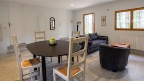 A dining area with a round table and chairs, a sofa, and a small side table.