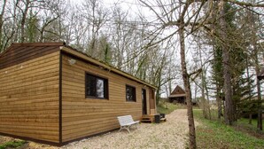 A wooden cabin with a gravel path leading to it, surrounded by trees.