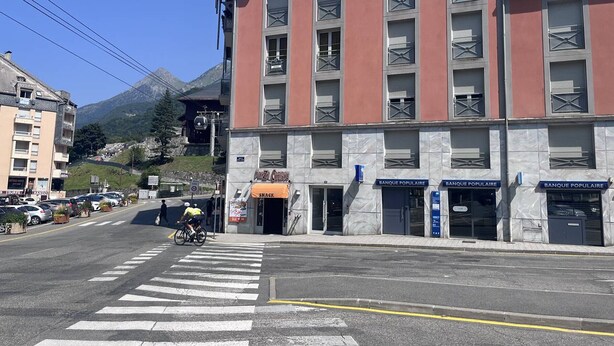 A multi-story building with a red facade, a snack bar on the ground floor, and multiple 'BANQUE POPULAIRE' signs.