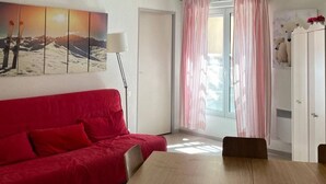 A room with a red sofa, a wooden table, and a window with pink curtains.
