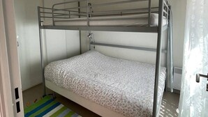 A bunk bed room with a striped rug and a window with curtains.