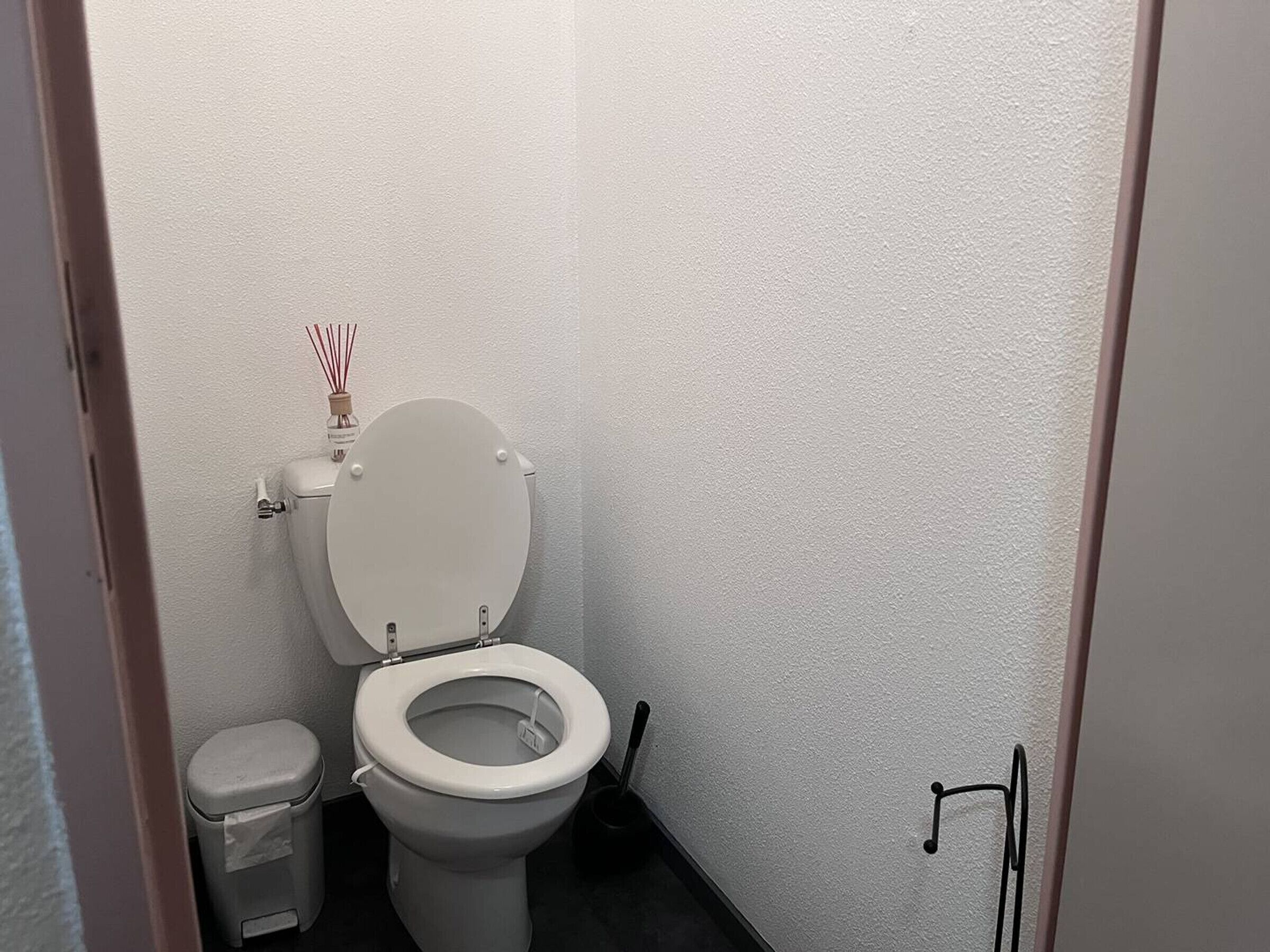 Un baño pequeño y limpio con inodoro, un cubo de basura y un bidé.
