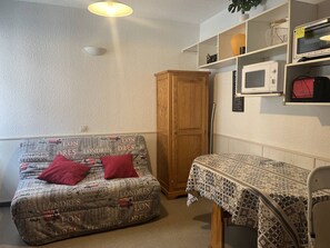 A compact living space with a sofa, a small table, a cabinet, and a microwave.